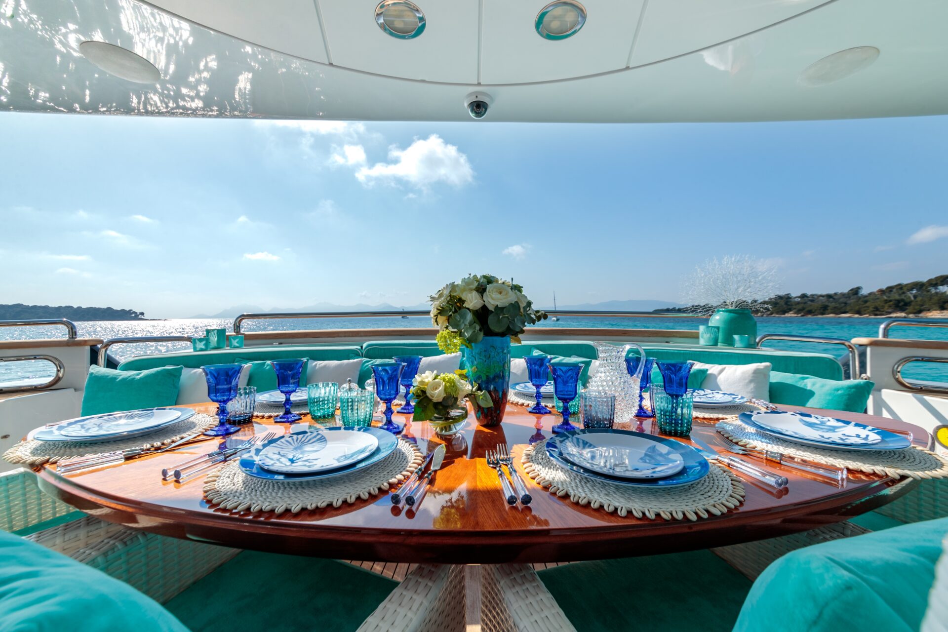 An ocean-themed table setting with blue plates, wine glasses and a flower bouquet on a luxury yacht