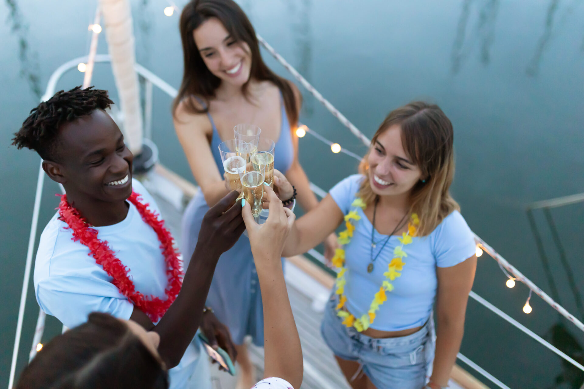 Friends enjoy a meal on a sailboat at sunset with a scenic water landscape in the background.