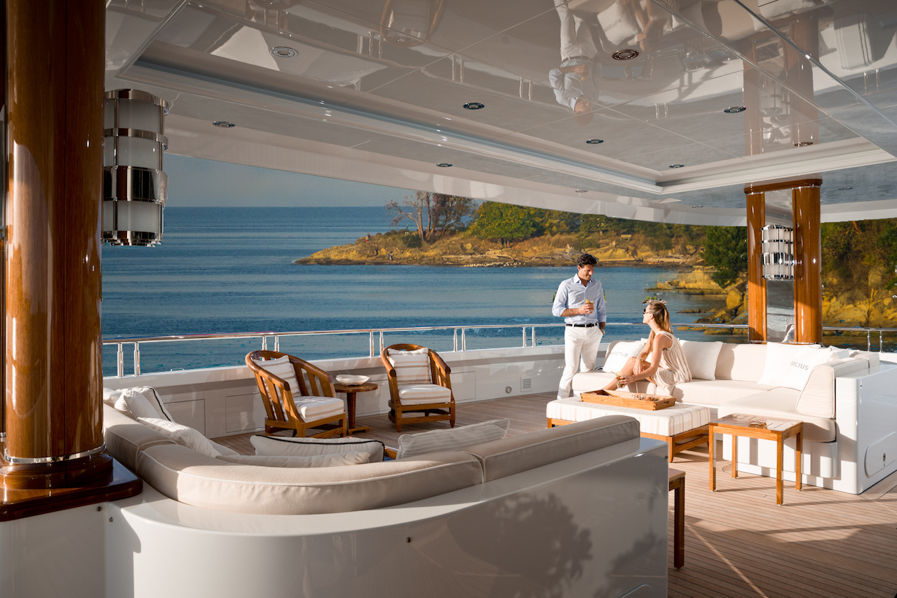 A couple enjoying a cozy meal on their yacht’s deck, with the autumn foliage of Galiano Island in the background.