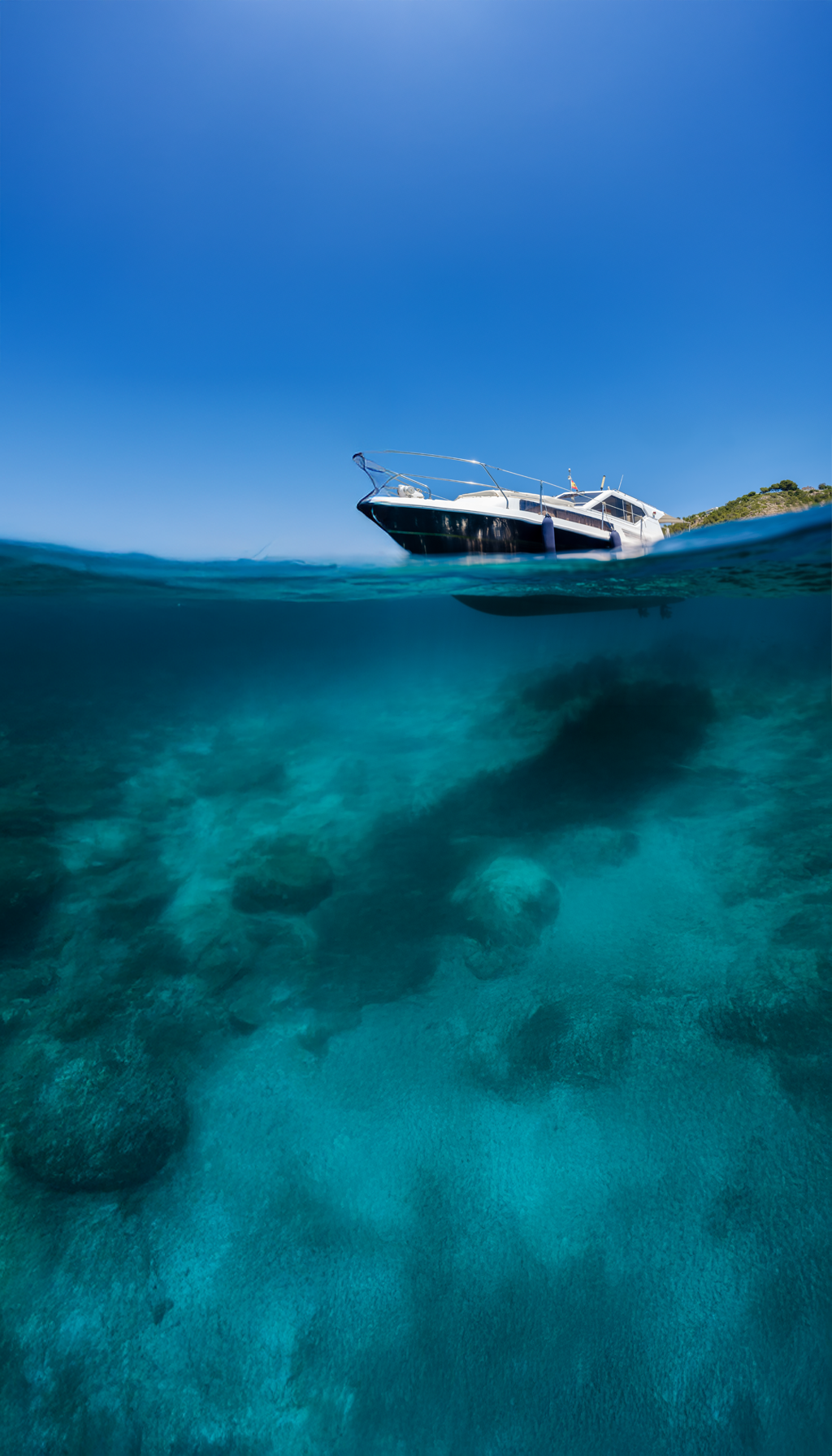 A stunning view of a luxury yacht sailing in crystal-clear waters, surrounded by lush, unspoiled marine life. The image symbolizes the harmony between yachting and nature that sustainable practices aim to achieve.