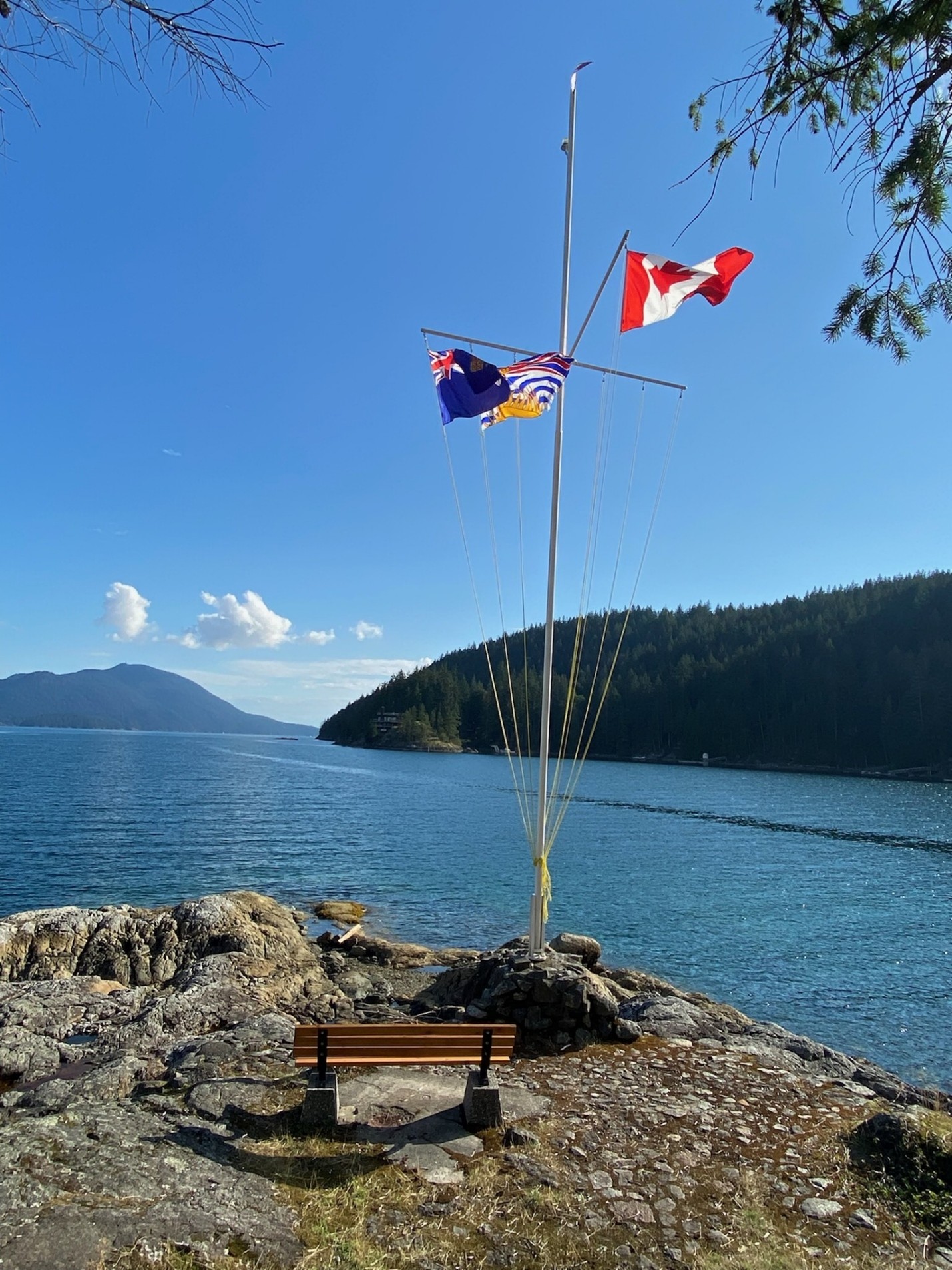Picture7 A picture of a sail mast anchored to a cliffside on a viewing area with the Australian, British Columbian, and Canadian flag attached.