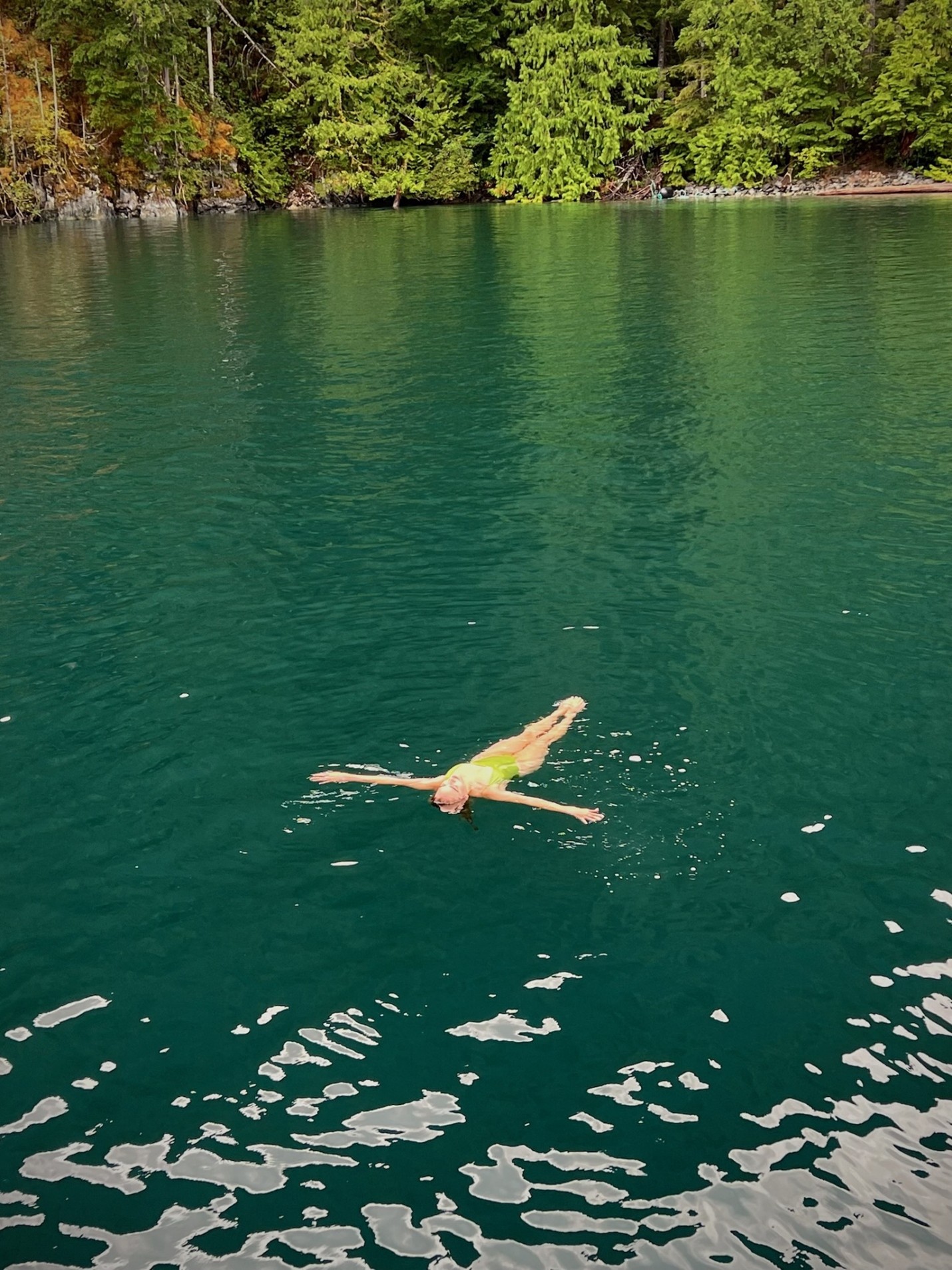 Shell Island - Lake A woman in a green bathing suit floating on a blue-green lake