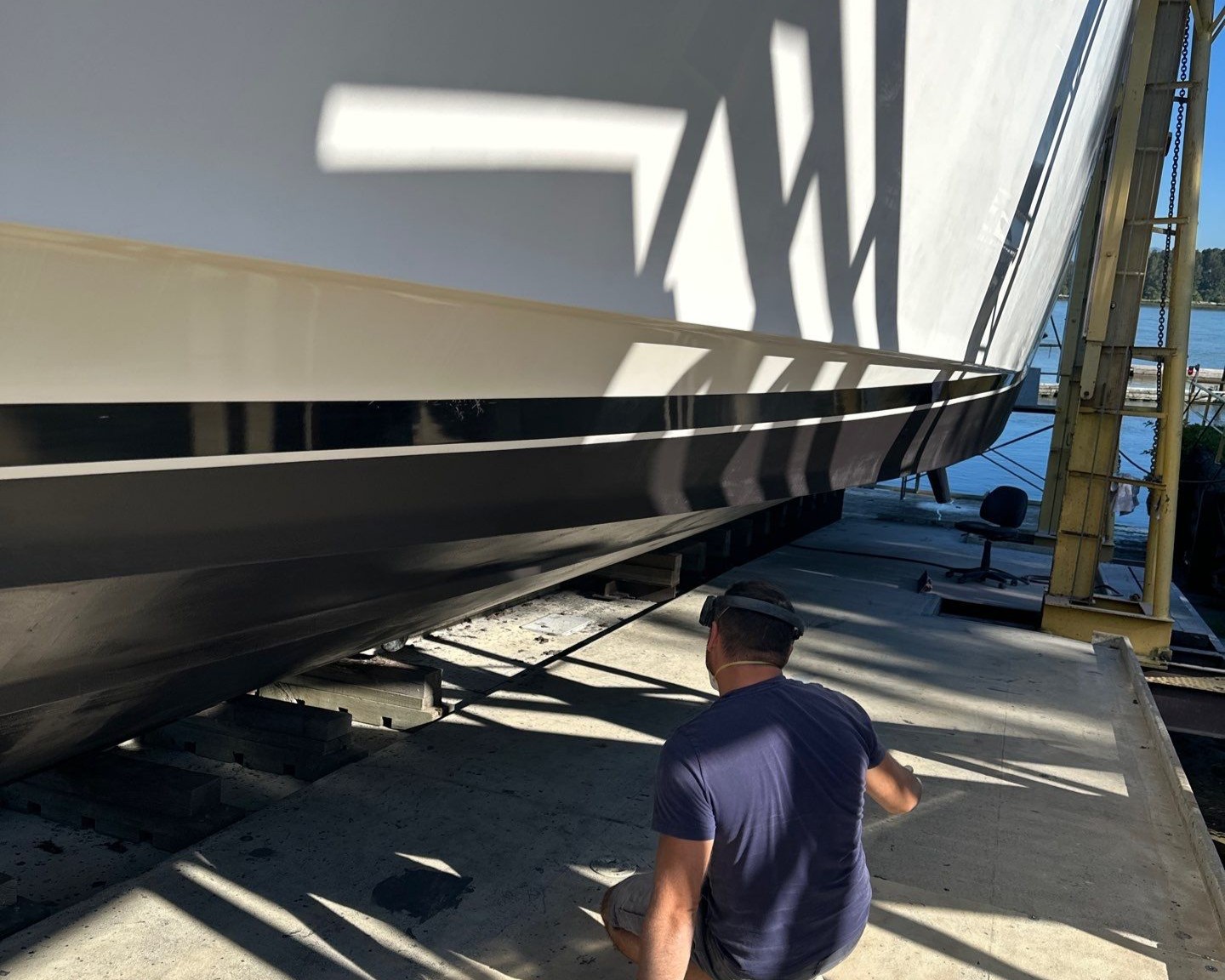 marine technician inspects the bottom hull of a yacht during a haul out